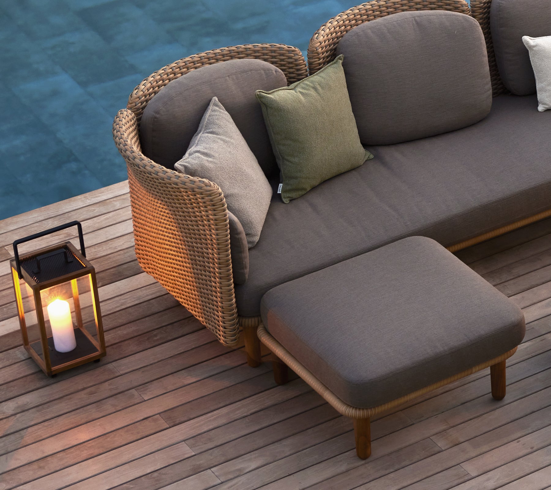 Ein gemütlicher Sitzbereich mit einem Sofa mit Kissen und einer Laterne, die die Atmosphäre mit warmem Licht verbessert.