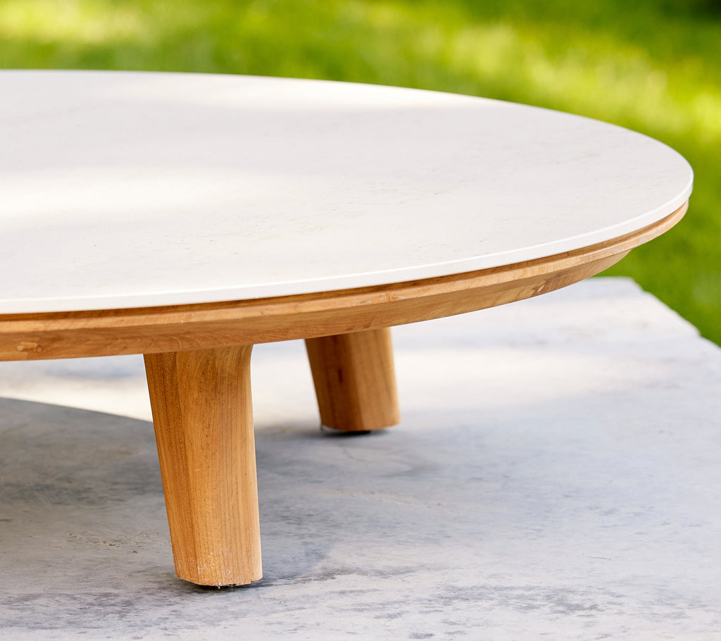 Nahaufnahme eines runden Couchtischs mit glatter Oberfläche und Holzbeinen, die sein elegantes Design und Handwerk hervorheben.