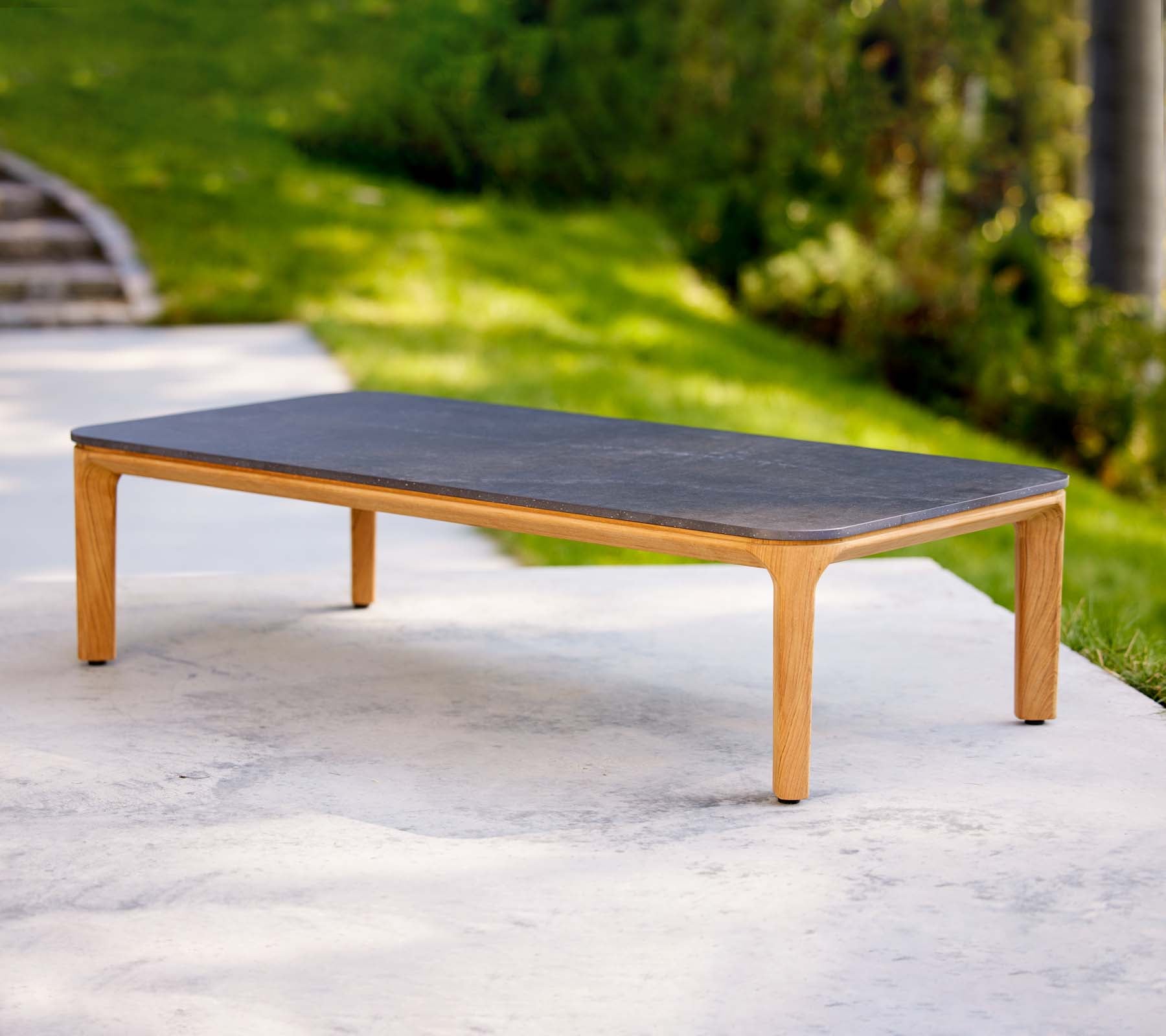 Ein schlanker Couchtisch mit einer dunklen Oberfläche und hellen Holzbeinen, ideal für moderne Wohnräume.