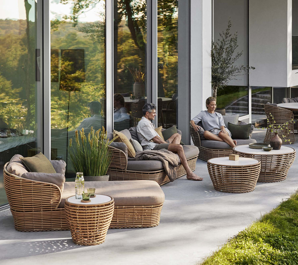 Eleganter Sitzbereich mit einem Korb-Sonnensessel, einem Loungesessel und einem Couchtisch mit natürlichen Elementen, der eine gemütliche, entspannende Atmosphäre schafft.
