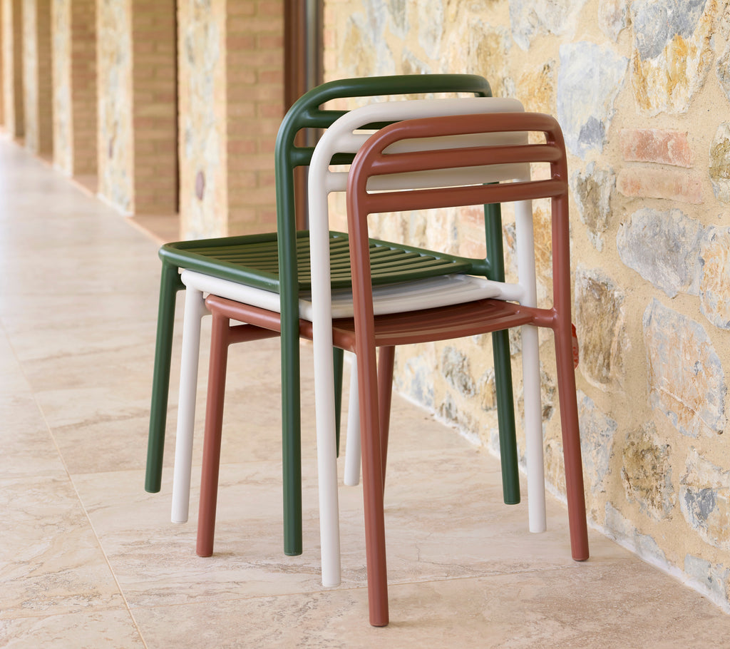 Ein Stapel Bliss-Stühle in verschiedenen Farben, die ein schlankes Design und praktische, platzsparende Lagerung zeigen.