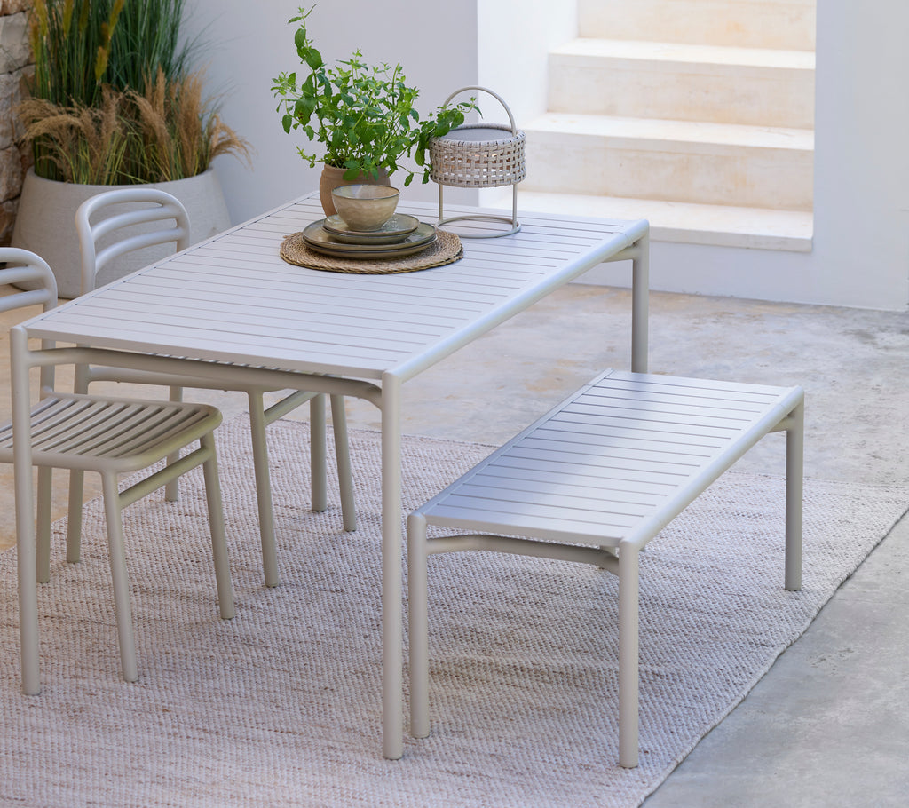 Modernes weißes Esstisch mit passender Bank und Stuhl in einem minimalistischen Ambiente.