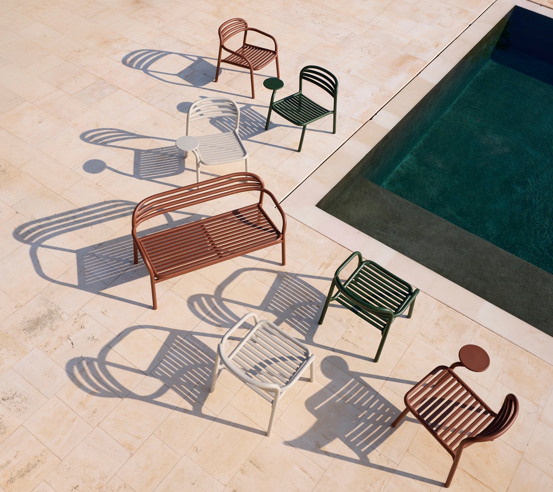 Set moderner roter, weißer, grüner Stühle und einer braunen Bank neben einem Pool.