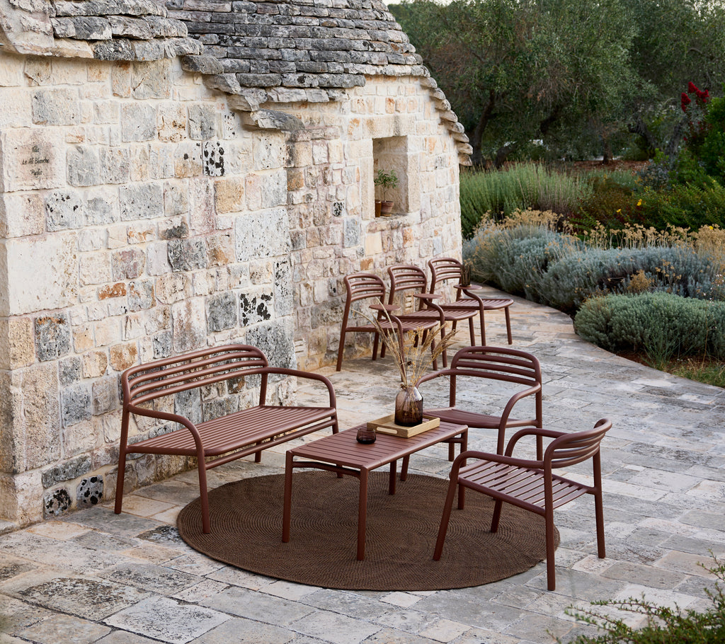 Braunes Outdoor-Sofa, Stühle und Tischset in einem modernen Lounge-Bereich.