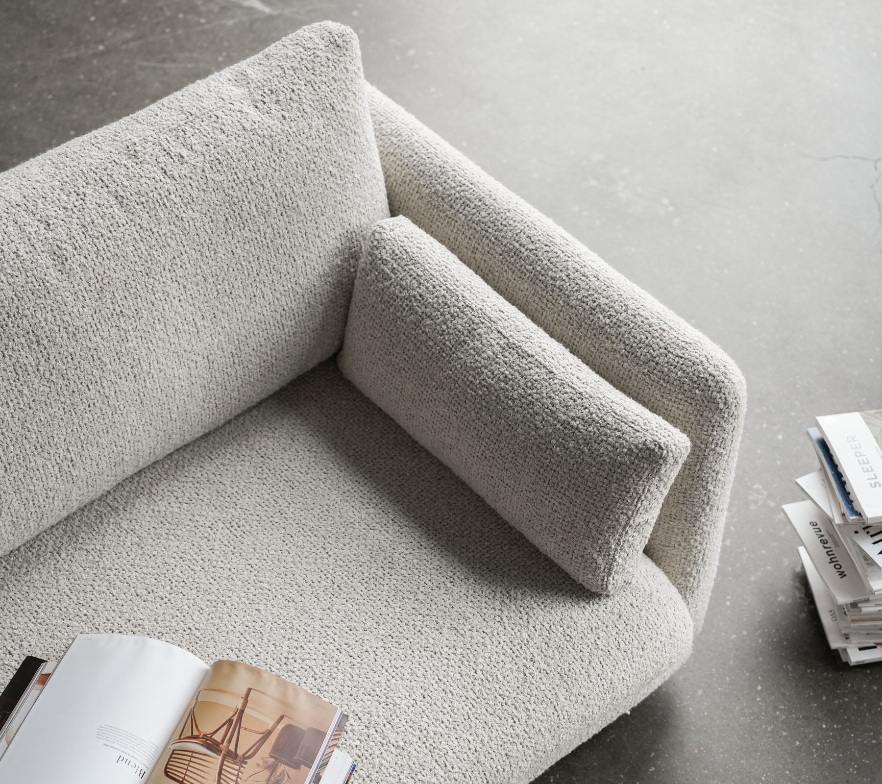 Stylische Sofa mit einer strukturierten Oberfläche, ausgestattet mit einer kuscheligen Armlehne und einem bequemen Kissen, perfekt zum Entspannen und Lesen.