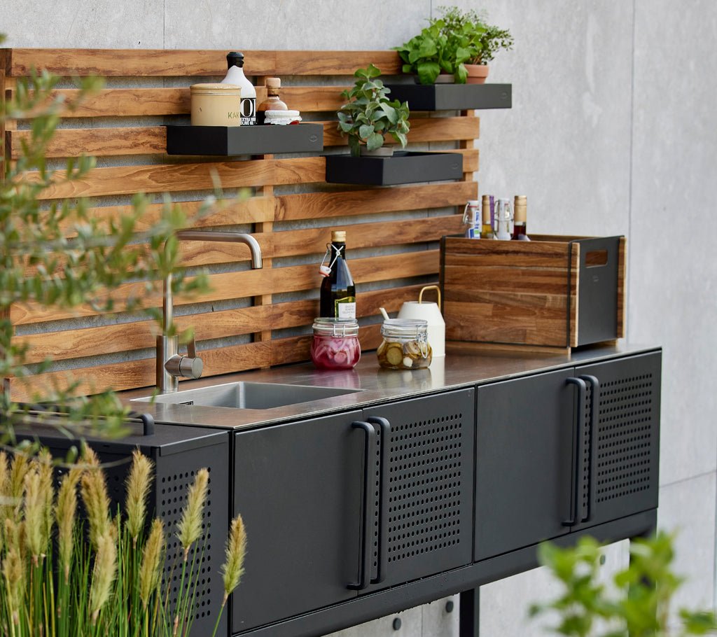 Schlichte Aufbewahrungsbox auf einer funktionalen Küchenarbeitsplatte mit Pflanzen und Gewürzen, die vor einem stilvollen Holz-Hintergrund präsentiert werden.