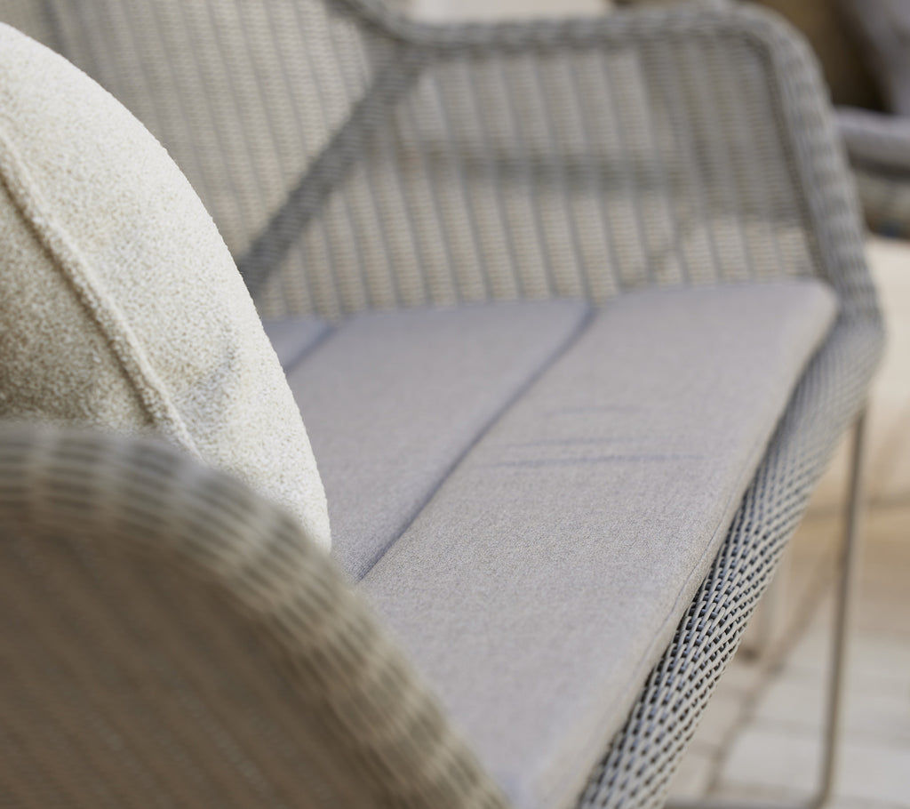 Moderne graue Sofa mit einem plüschigen Kissen in einem stilvollen Lounge-Ambiente.