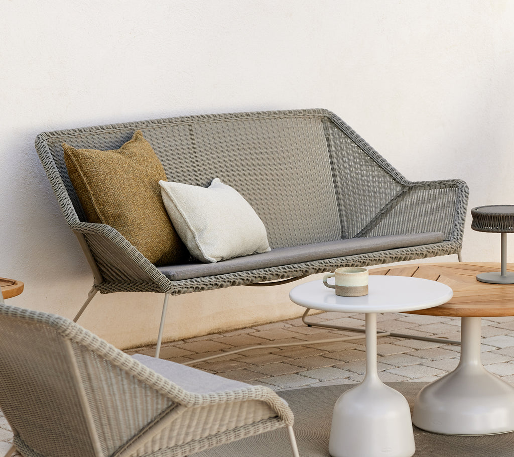 Modernes Lounge-Bereich mit einem grauen Sofa mit Kissen und runden Tischen.