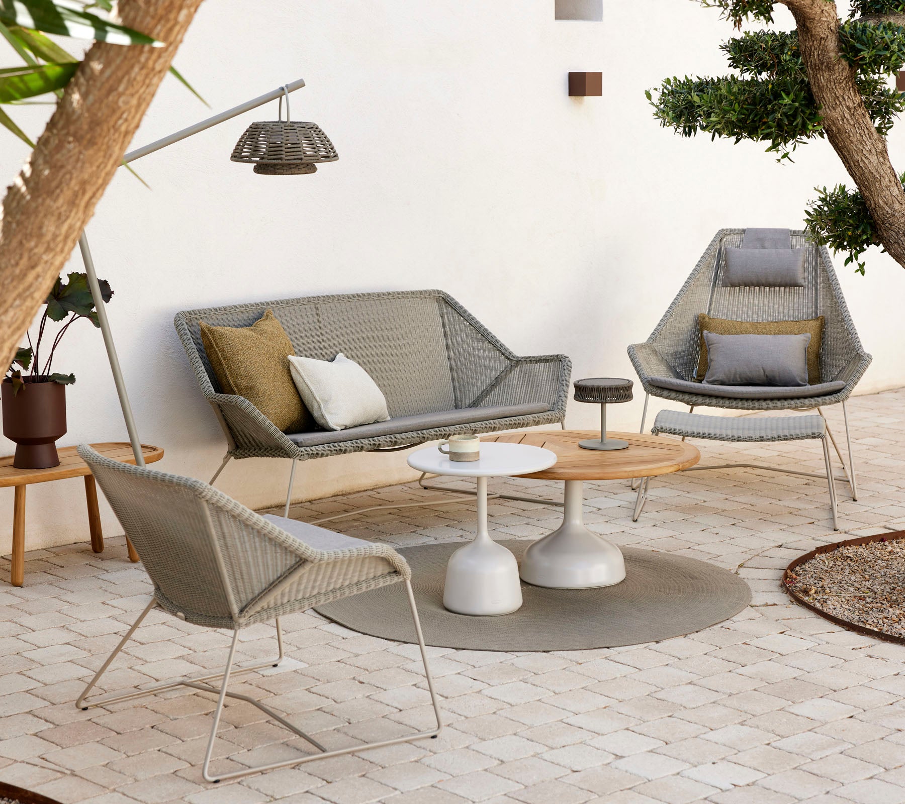 Stilvolle Lounge-Sitzgelegenheiten mit einem Couchtisch, ausgestattet mit strukturierten Kissen und natürlichen Tönen, umgeben von Grünpflanzen und sanfter Beleuchtung.