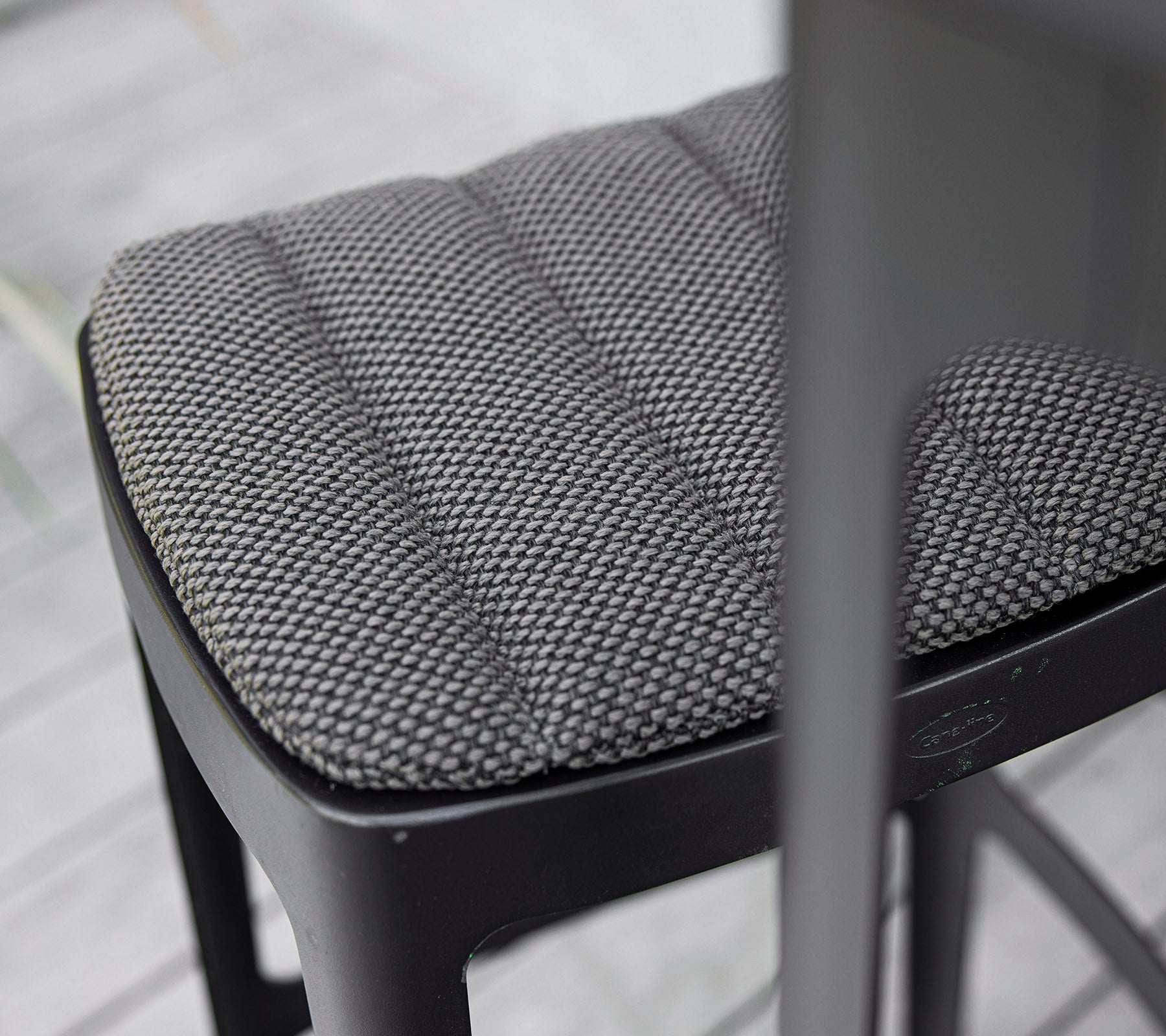Nahaufnahme eines strukturierten schwarzen Stuhlsitzes mit einem gesteppten Design, das modernes Handwerk und Liebe zum Detail zeigt.