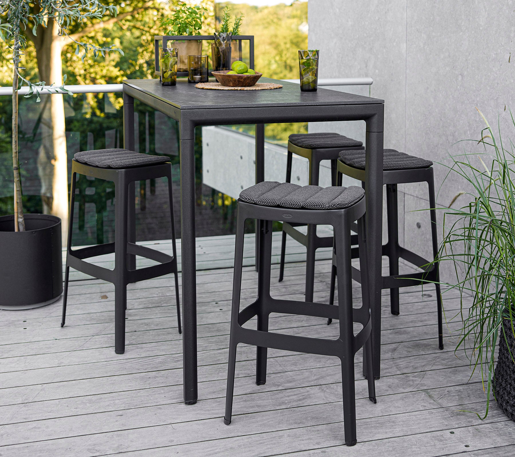 Ein moderner Tisch mit vier passenden Hockern, der ein schlankes Design und eine minimalistische Ästhetik aufweist, vor einem natürlichen Hintergrund.