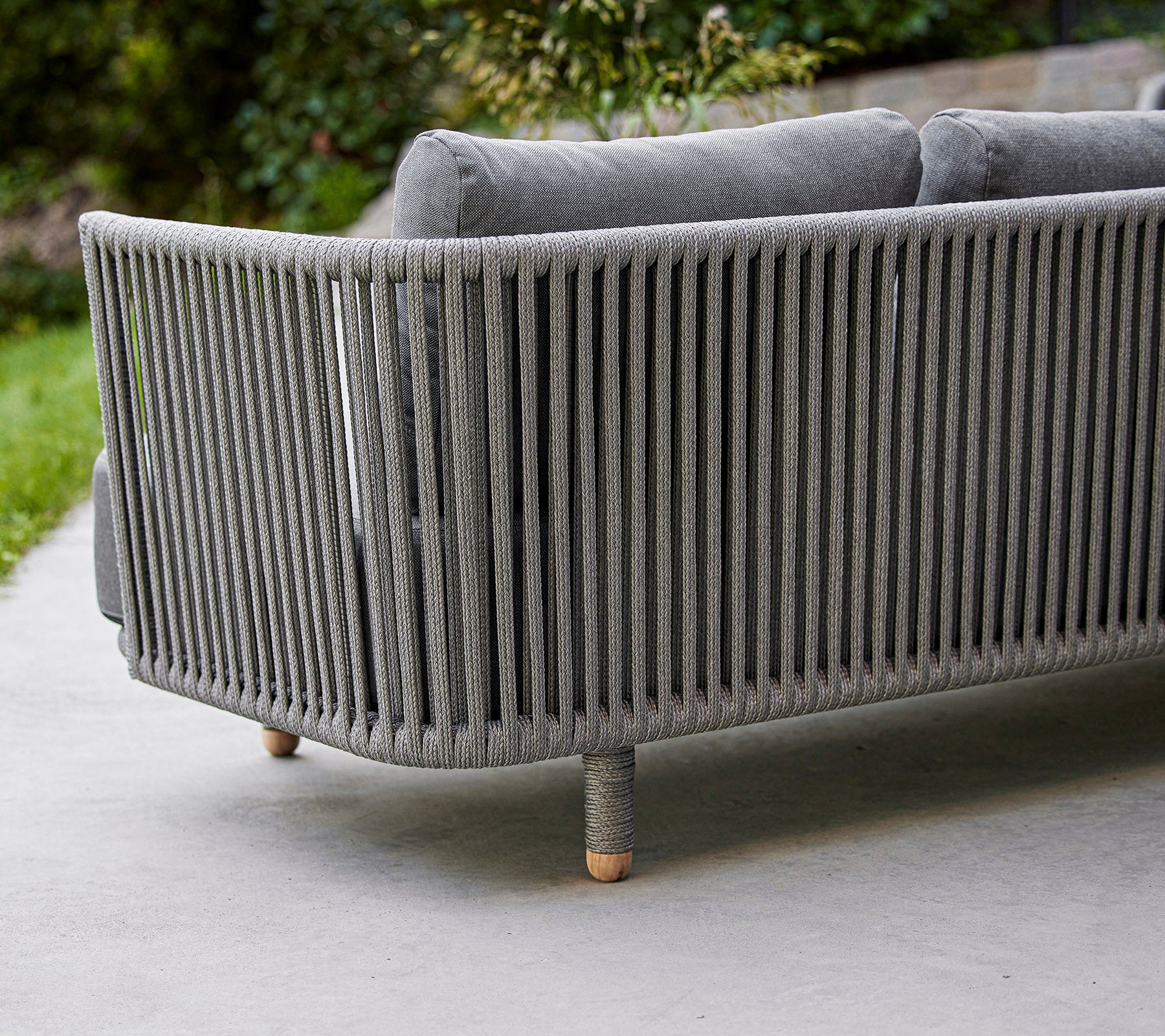 Schlanker, moderner grauer Sofa mit vertikalen Lamellen-Design und Holzbeinen, ideal für zeitgenössische Außen- oder Wohnräume.