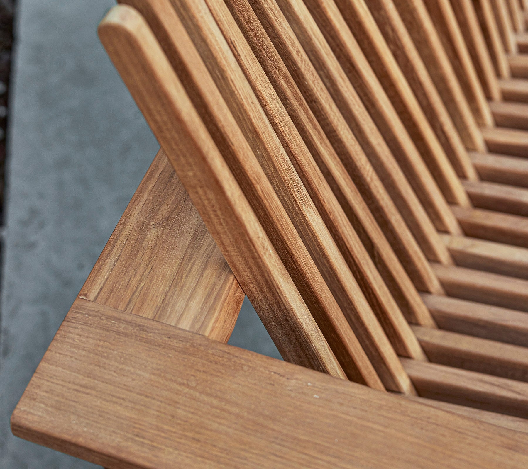 Nahaufnahme eines Holzmöbelstücks mit lamellenartigem Design, das die natürliche Maserung und Handwerkskunstdetails zeigt.