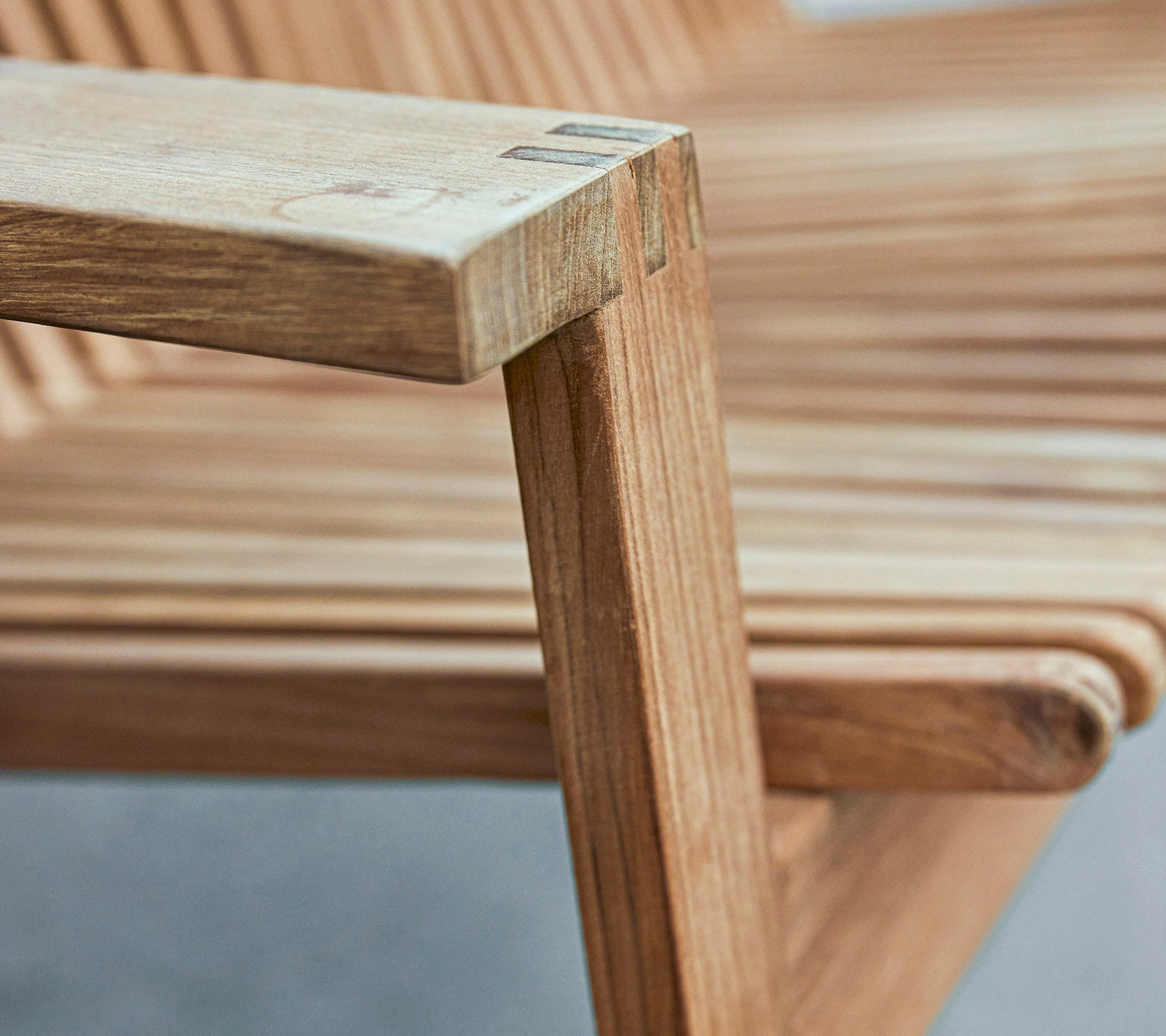 Nahaufnahme einer Holzstuhlarmlehne, die ein schlankes Design mit lamellierter Sitzfläche und glatten Oberflächen zeigt.