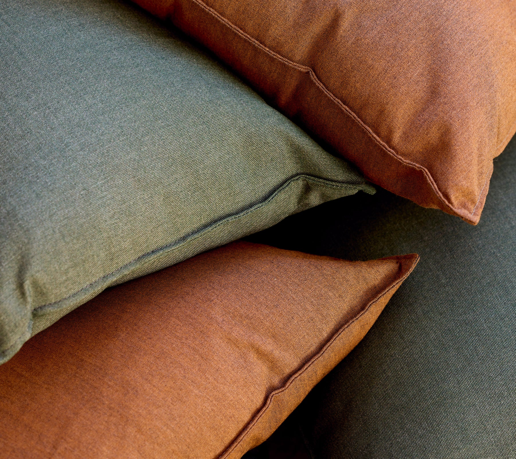 Stapel aus grünen und braunen Kissen, die zusammen angeordnet sind.