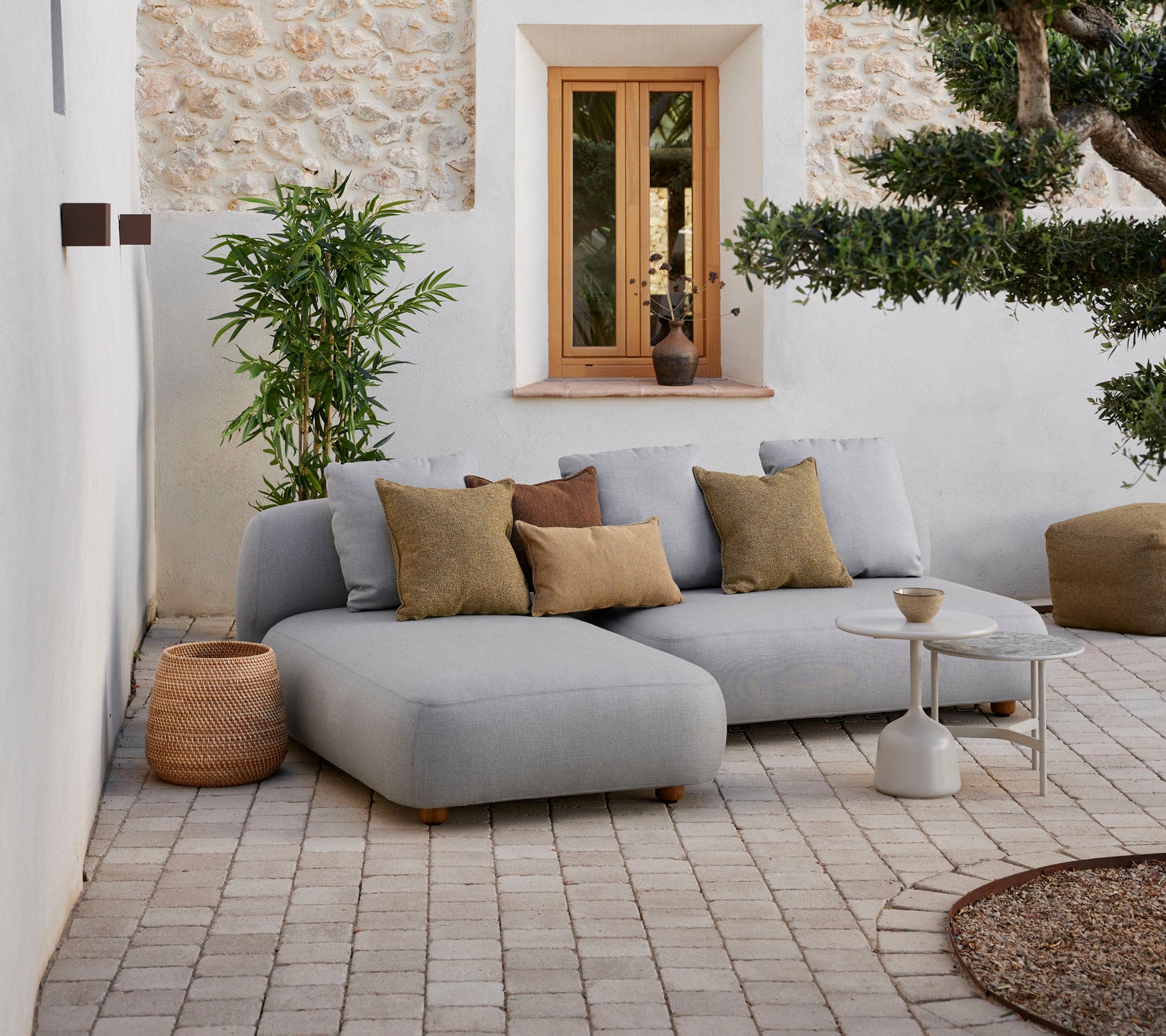 Moderne graues Ecksofa mit dekorativen Kissen, kleinem Beistelltisch und natürlichen Elementen in einem gemütlichen Ambiente.