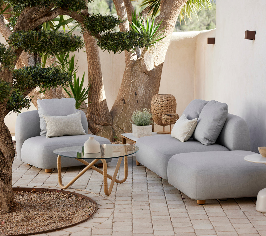 Moderne graues Sofa und Stuhl mit einem Glastisch in einem stilvollen Außenlounge-Bereich.