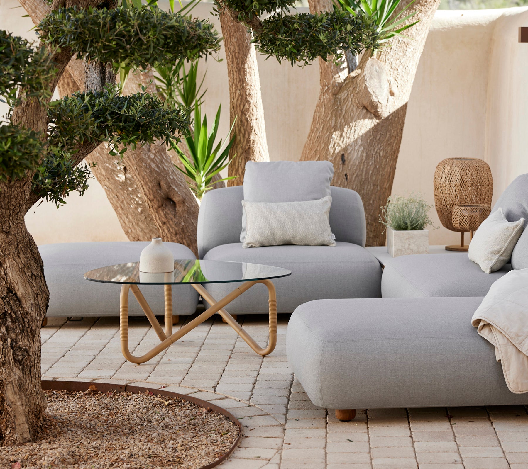 Modernes Lounge-Bereich mit einem grauen Sofa, weißem Kissen und Glastisch.