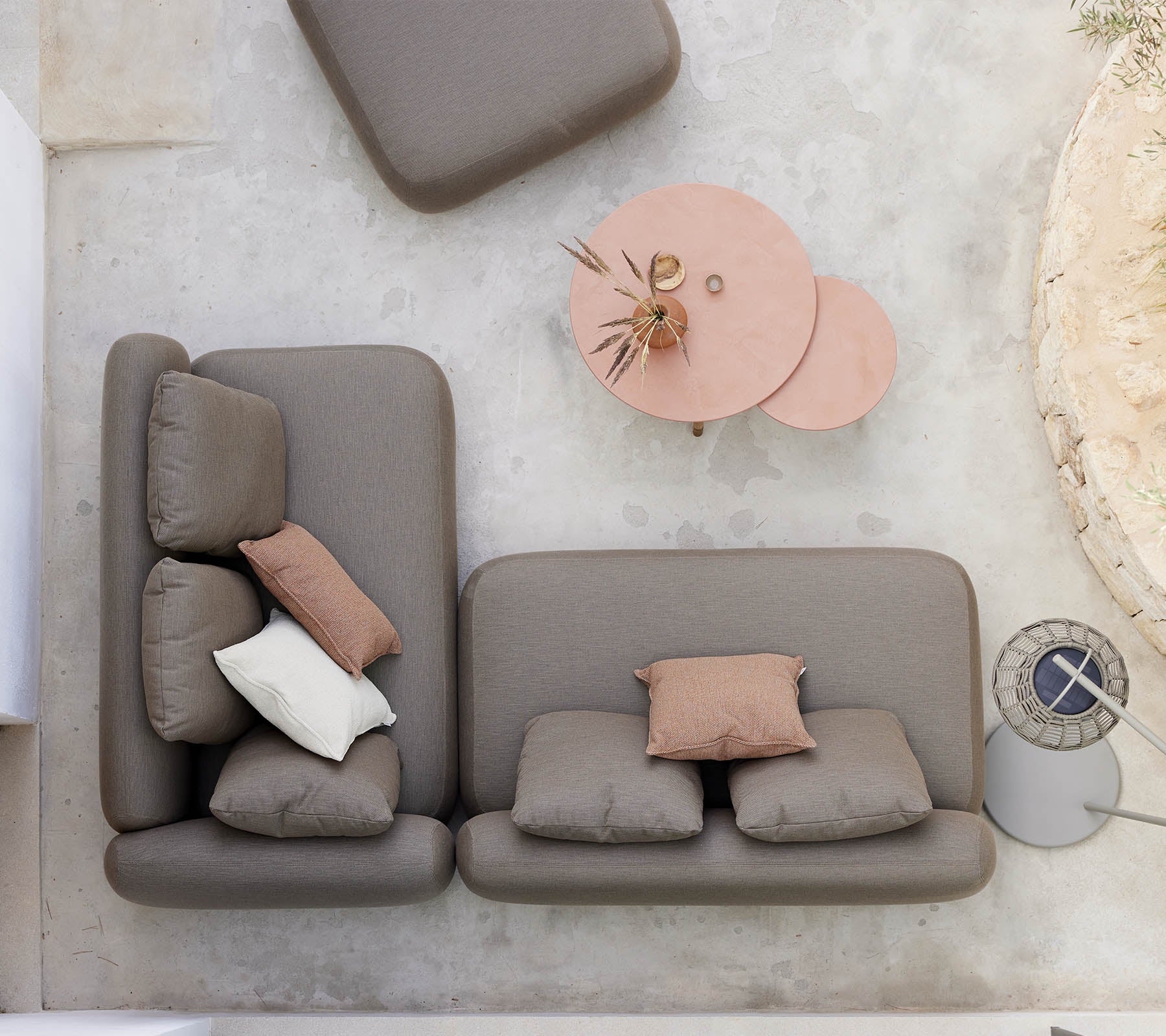 Eine stilvolle Sitzgelegenheit mit einem neutralfarbenen Sofa mit dekorativen Kissen, begleitet von einem einzigartigen Twist-Couchtisch.