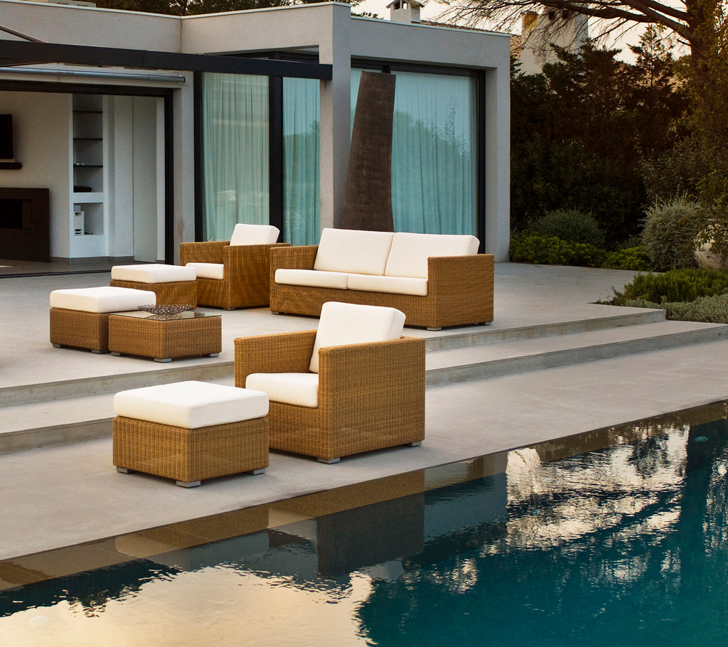 Moderne Außenlounge-Bereich mit braunem Sofa, Stühlen und Kissen am Pool.