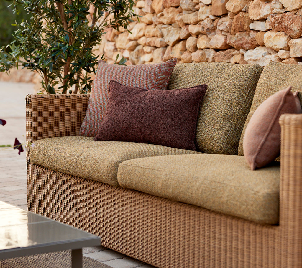 Moderne beige Sofa mit lila und braunen Kissen in einer Lounge-Einstellung.