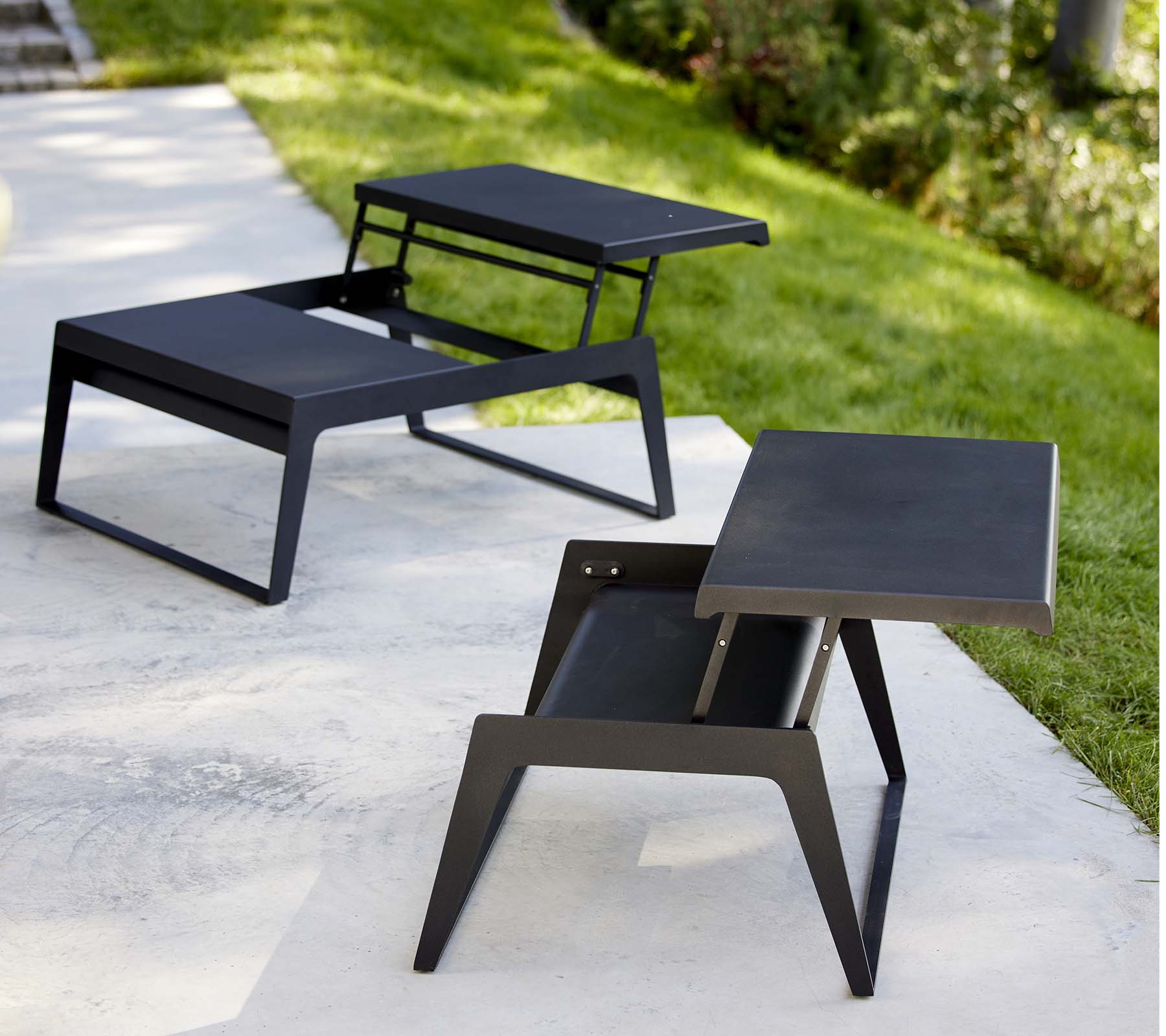 Zwei moderne Chill-Out-Couchtische mit schlankem Design und minimalistischer schwarzer Oberfläche, die Vielseitigkeit in Stil und Funktionalität zeigen.