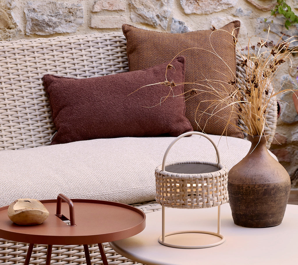 Gemütliches Küsten-Sofa mit strukturierten Kissen, einer dekorativen Vase und einem stilvollen Couchtisch mit einem geflochtenen Korb und einem glatten Stein.