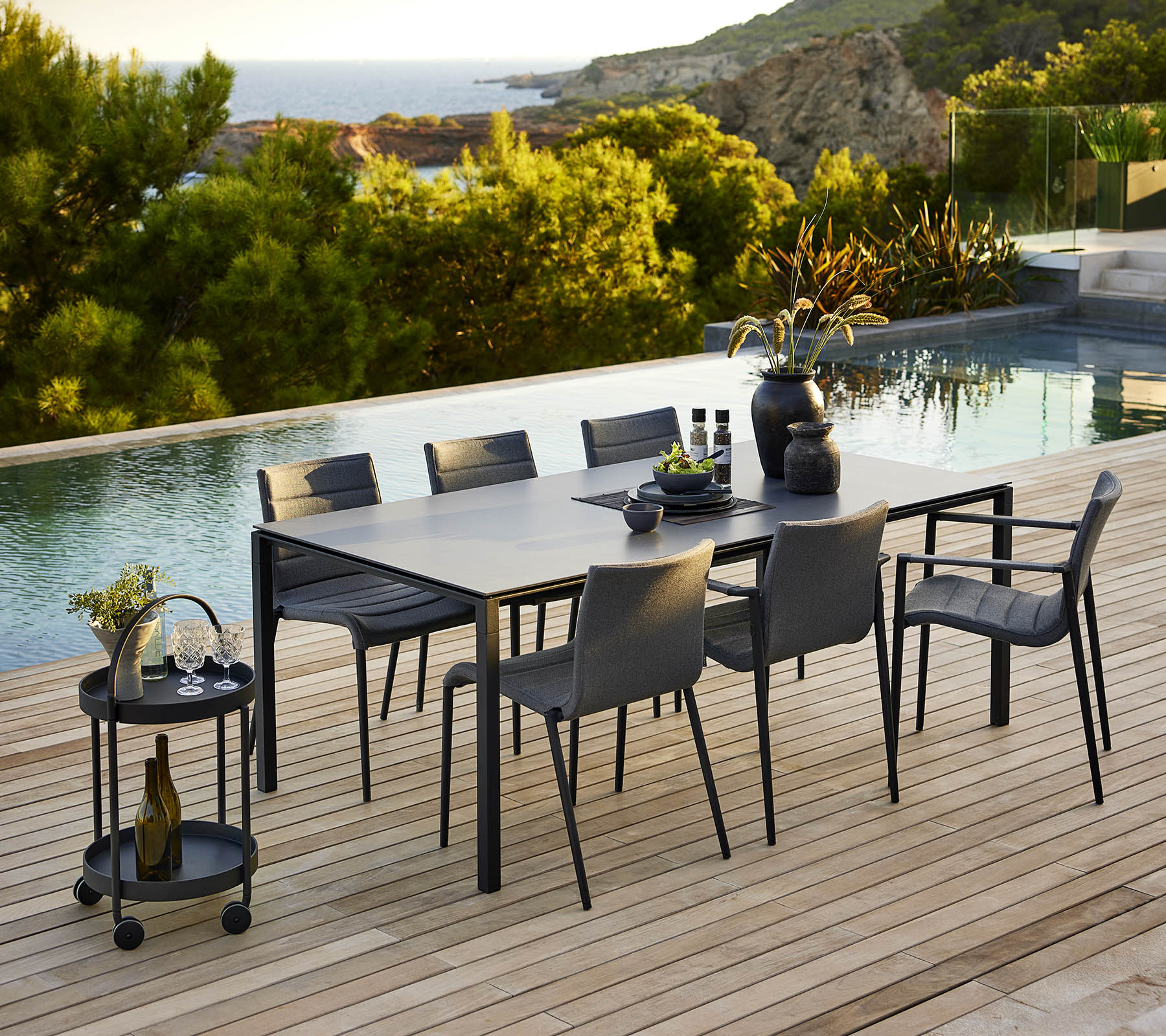 Stilvolles Ess-Setup mit einem schlanken Tisch und passenden Stühlen, ergänzt durch dekorative Accessoires und eine ruhige Outdoor-Kulisse.