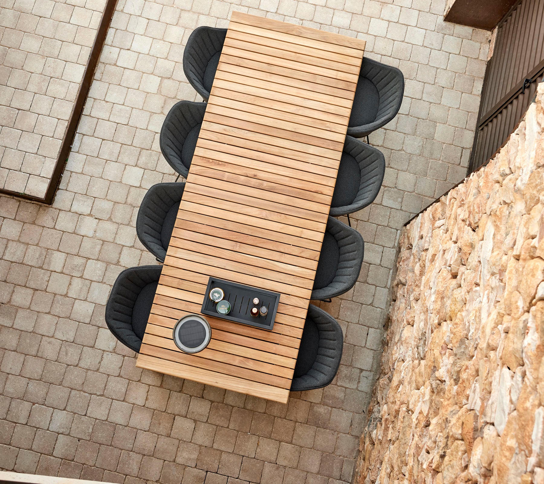 Ein langer Holztisch mit sleekem Design, umgeben von vier modernen Stühlen, mit einem dekorativen Mittelpunkt.