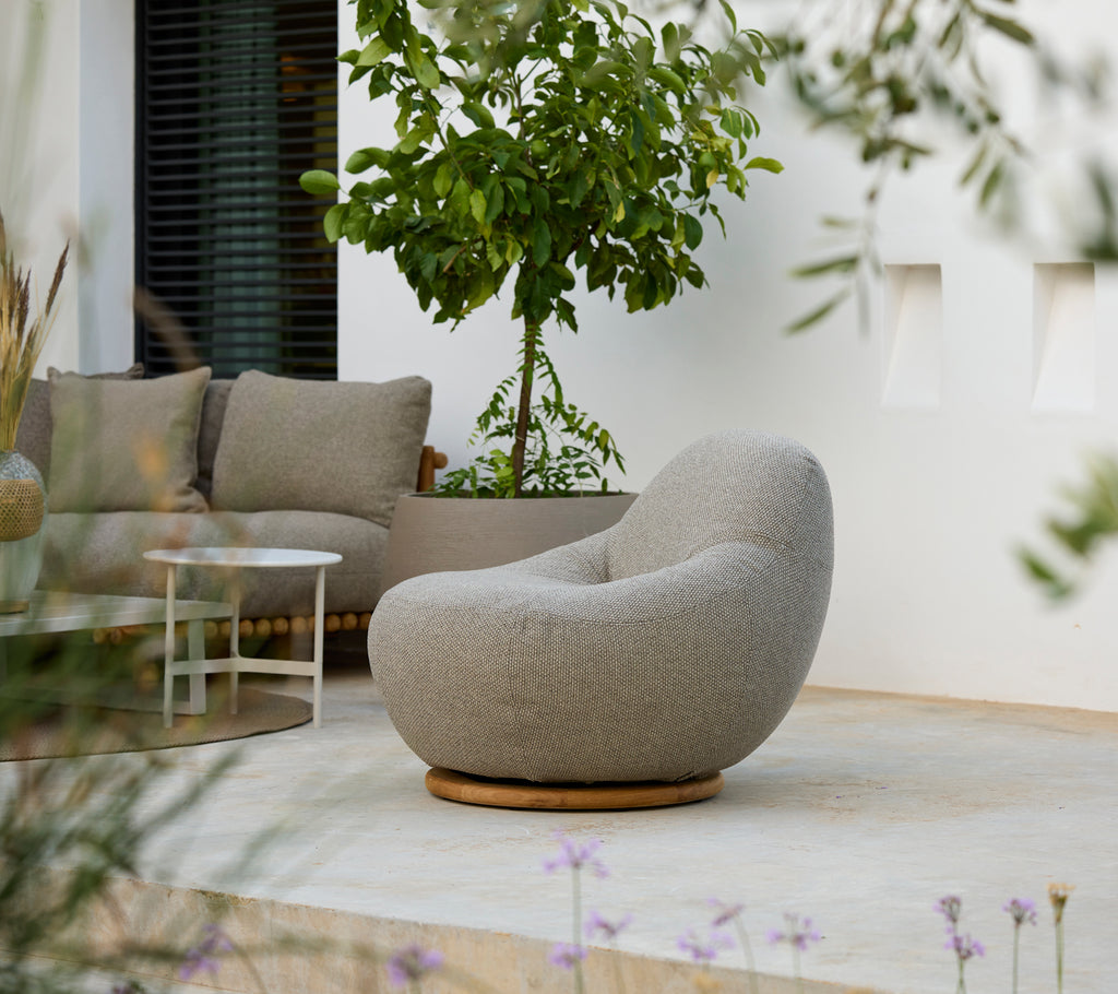 Moderne Lounge-Einrichtung mit einem grauen Stuhl, grauem Kissen und weißem Tisch.