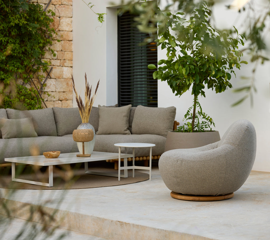 Moderner Loungebereich mit einem grauen Ecksofa, einem weißen Couchtisch und einem runden Stuhl.