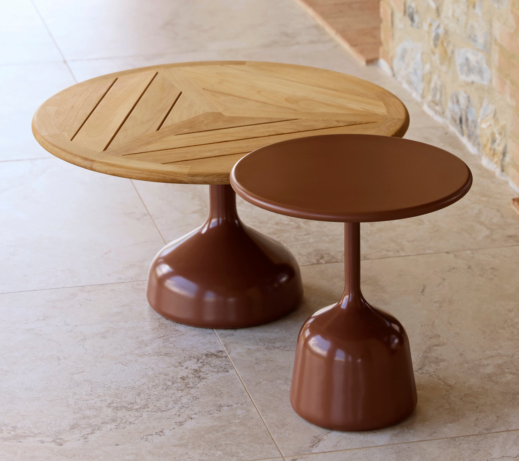 Zwei Couchtische, einer mit einer Holzplatte und geometrischem Design, der andere mit einer glatten, wüstenroten Oberfläche, die eine moderne Ästhetik teilen.