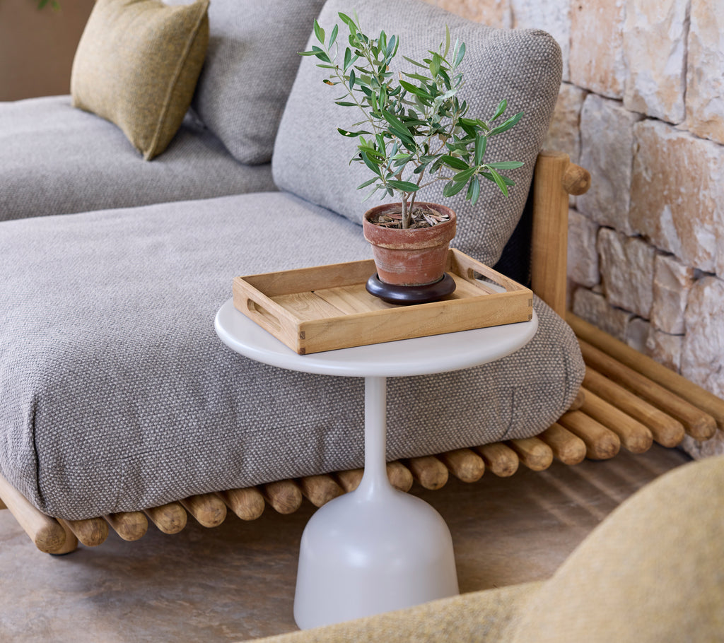 Moderne Lounge-Einrichtung mit einem grauen Sofa, einem weißen Beistelltisch und einer grünen Pflanze.