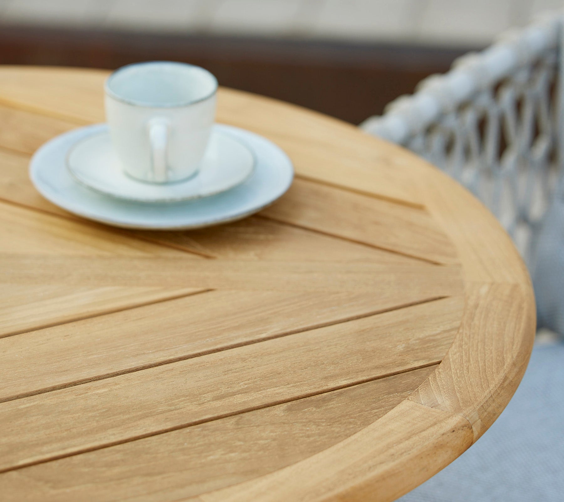 Ein Holztisch mit einer Kaffeetasse und Untertasse darauf, der ein minimalistisches und einladendes Café-Setting zeigt.
