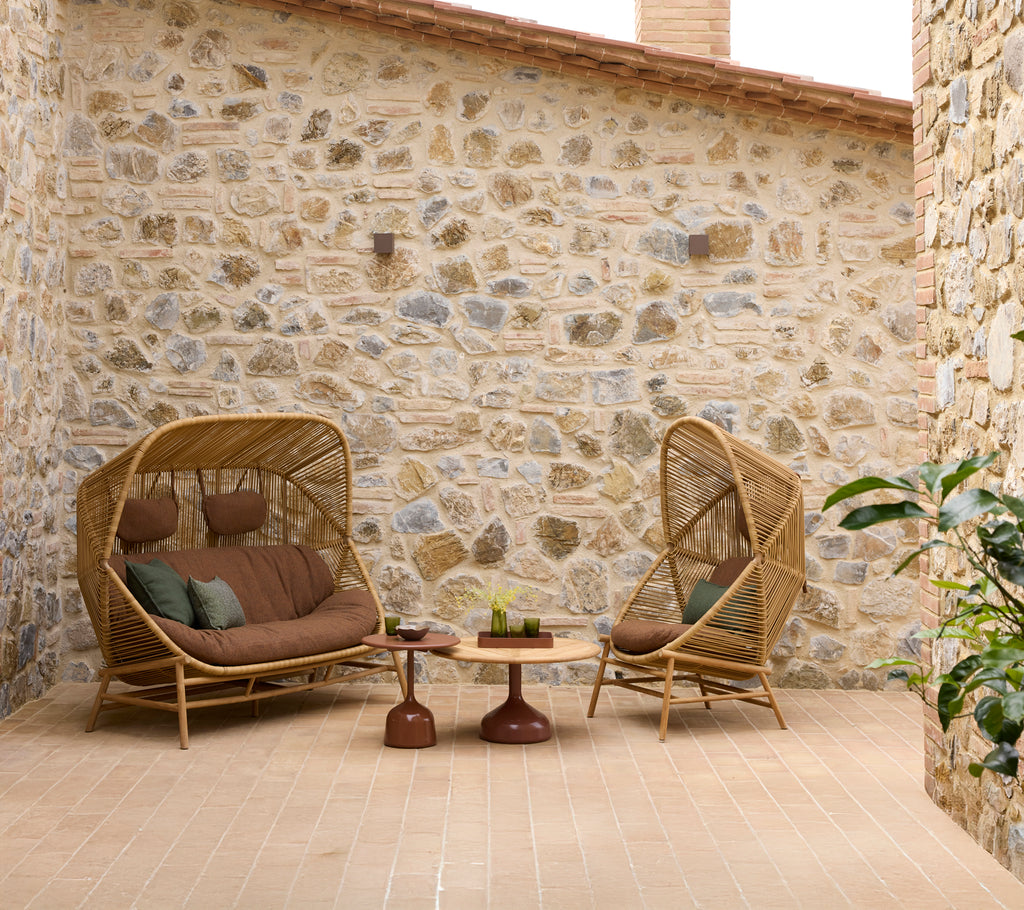 Eine gemütliche Sitzecke mit Hive-Schaukelstühlen und einer Hive-Couch, ergänzt durch Glaze- couchtische und eine Steinwand im Hintergrund.