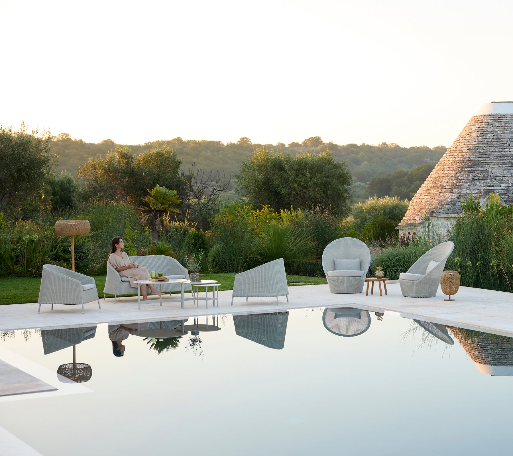 Moderne Außenlounge-Bereich mit grauen Stühlen und einem weißen Tisch neben einem Pool.