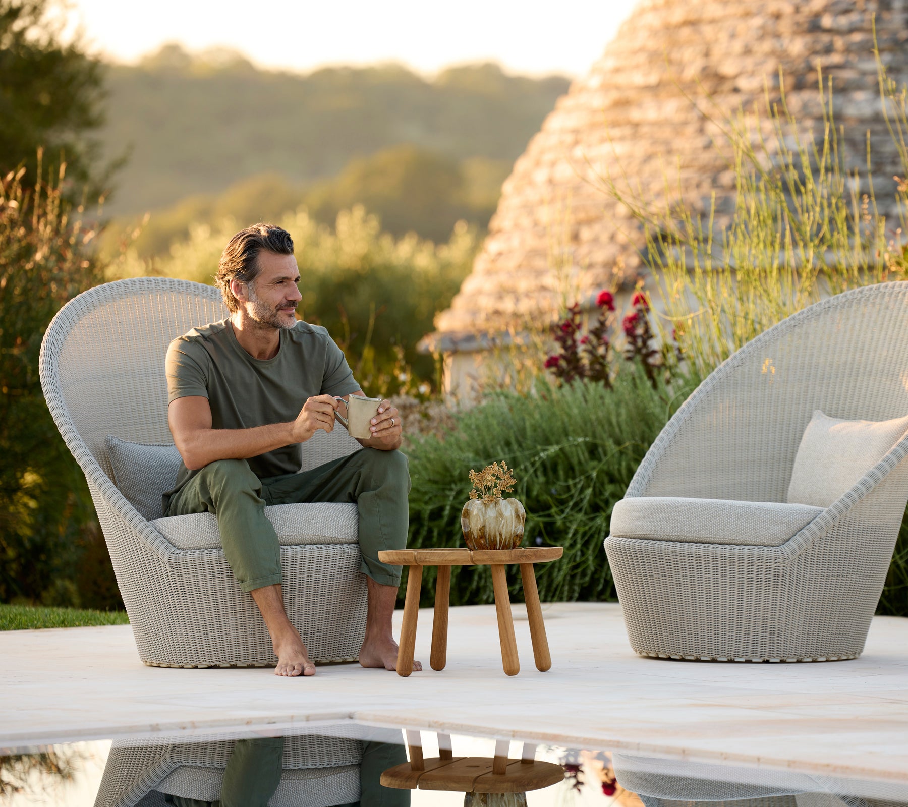 Moderne graue Loungesessel mit einem Holztisch neben einem Pool.