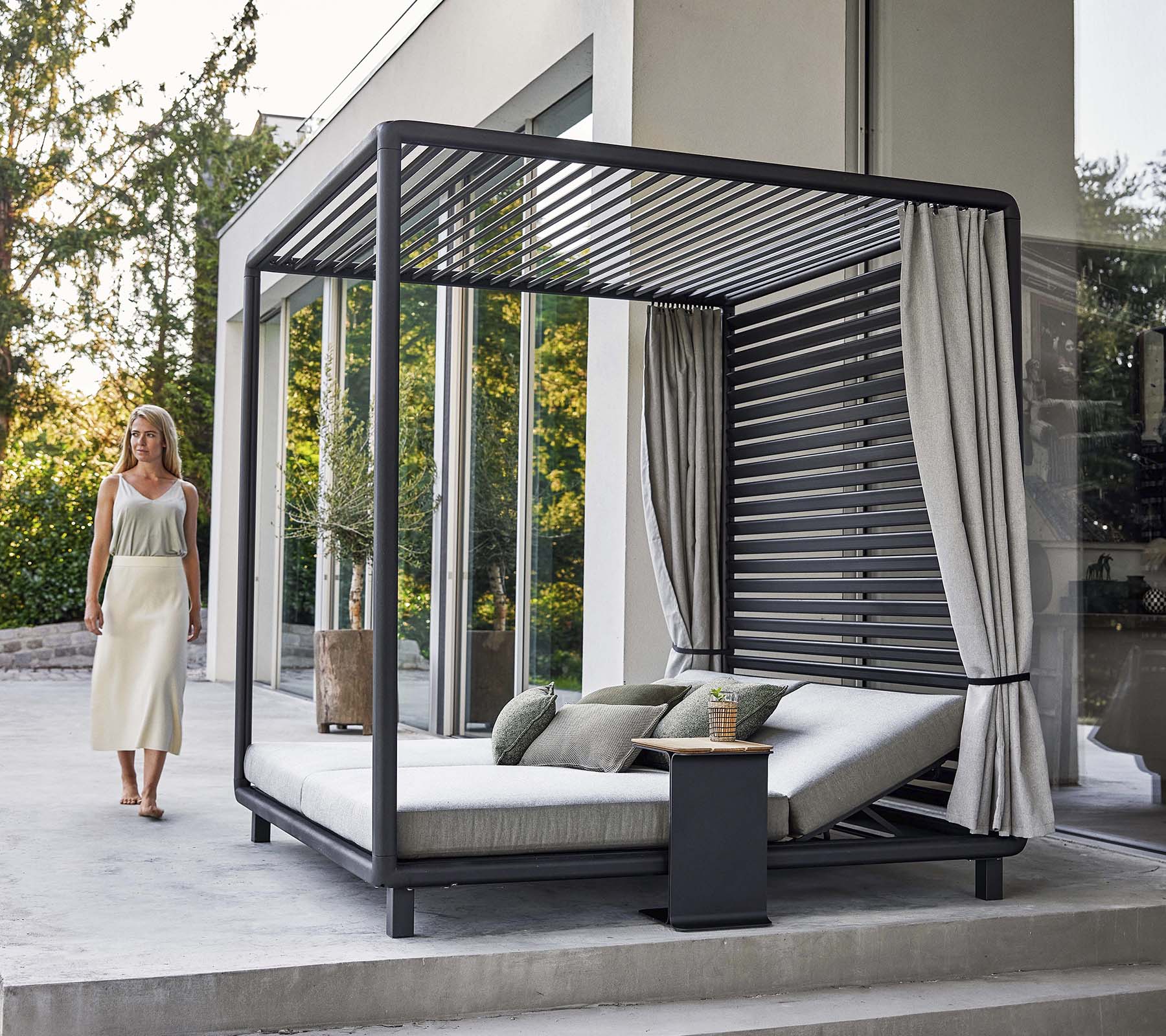 Eine stilvolle Cabana mit modernem Design, die einen komfortablen Loungebereich und weiche Vorhänge bietet, gelegen in einer ruhigen Umgebung.