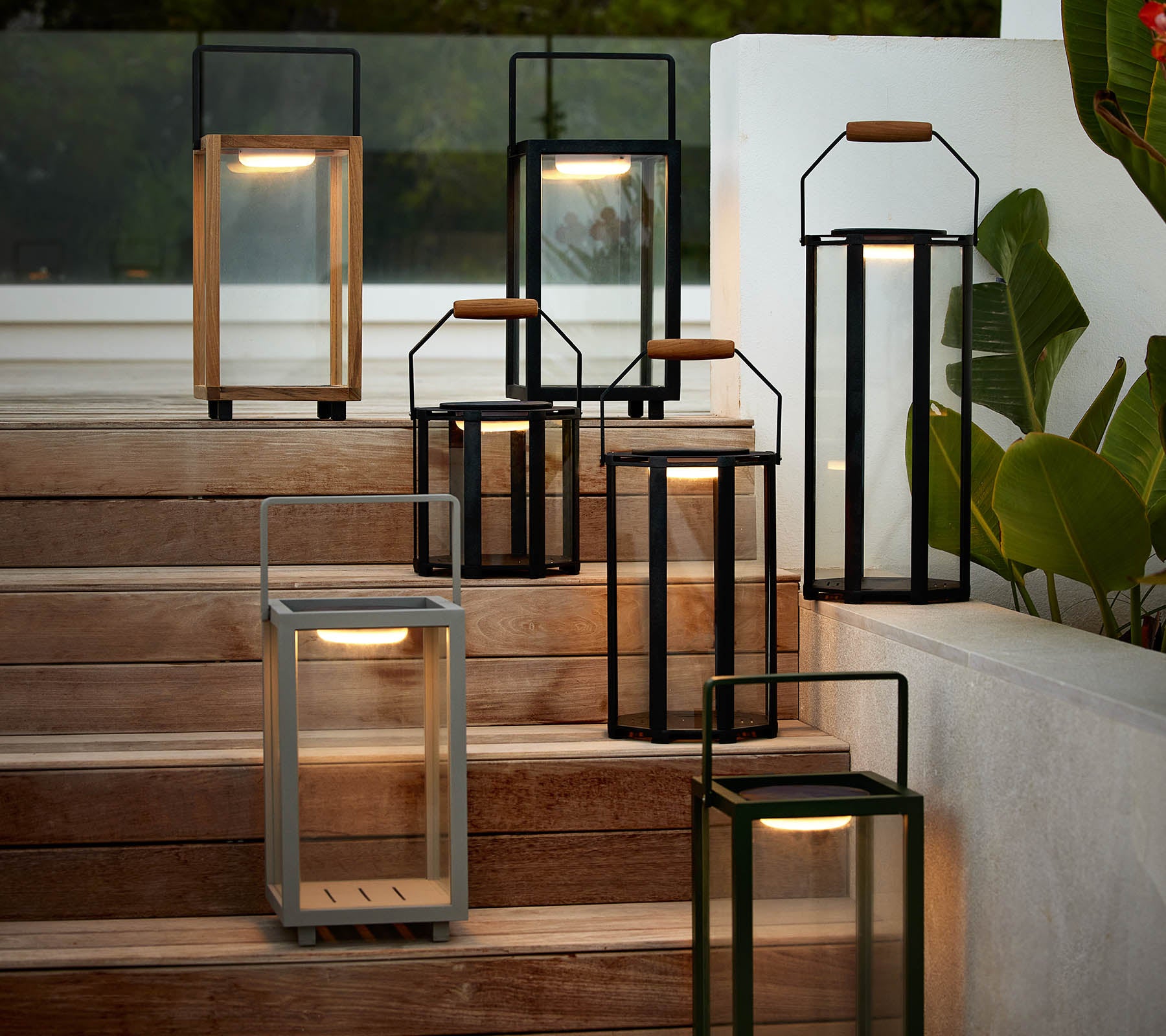 Eine Sammlung moderner Laternen in verschiedenen Stilen und Farben, die auf einer Treppe angeordnet sind und ihr elegantes Design sowie die warme Beleuchtung hervorheben.