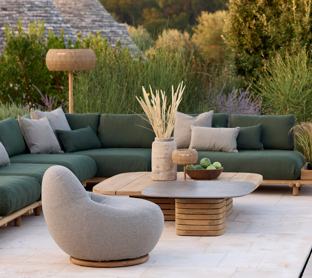 Moderner Loungebereich mit einem grünen Sofa, einem grauen Stuhl und einem runden Couchtisch.