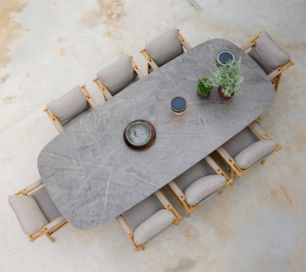 Moderne Essbereich mit einem grauen Tisch, beigen Kissen und Holzhockern.