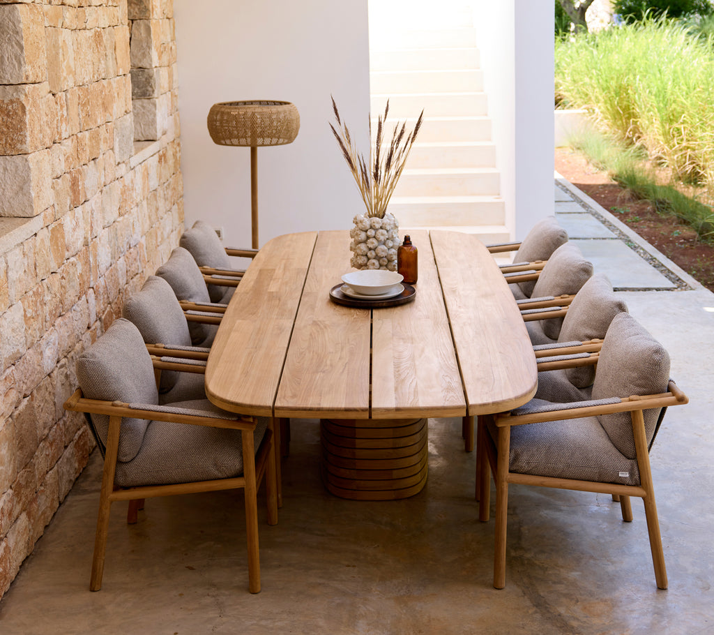 Moderne Essbereich mit Holztisch, grauen Kissen und Holzstühlen.