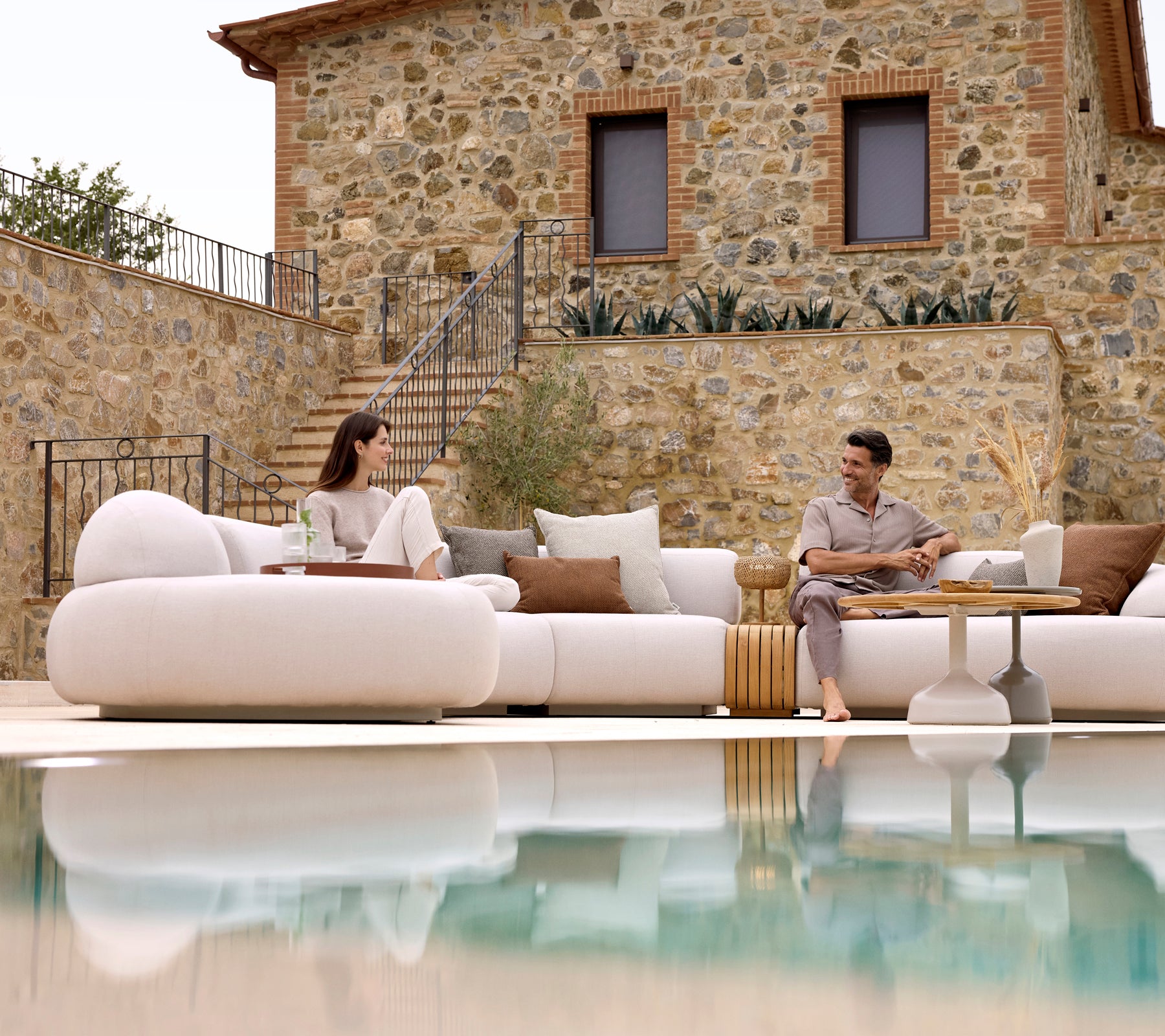 Zwei Personen entspannen sich auf einem gemütlichen Loungesofa, kombiniert mit einem Glaze-Couchtisch und einem gemütlichen Couchtisch, die eine ruhige Atmosphäre widerspiegeln.