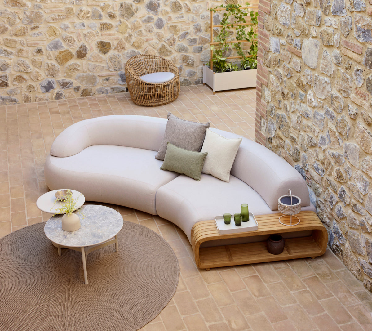 Gekrümmtes, sanftes Sofa mit dekorativen Kissen, ein sanfter Couchtisch und ein runder Neststuhl, auf einem strukturierten Boden.