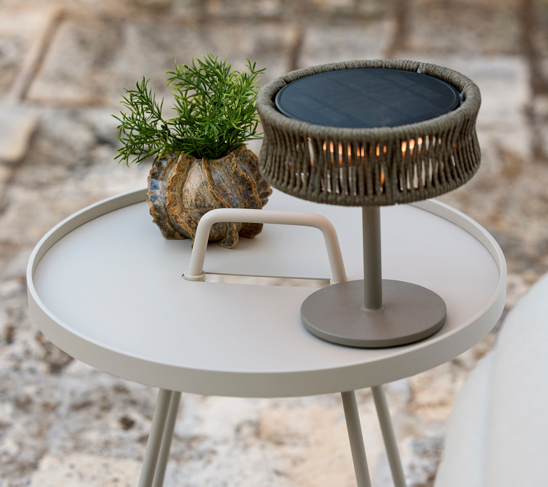 Moderne grauer Beistelltisch mit einer grünen Pflanze und einer stilvollen Tischlampe.