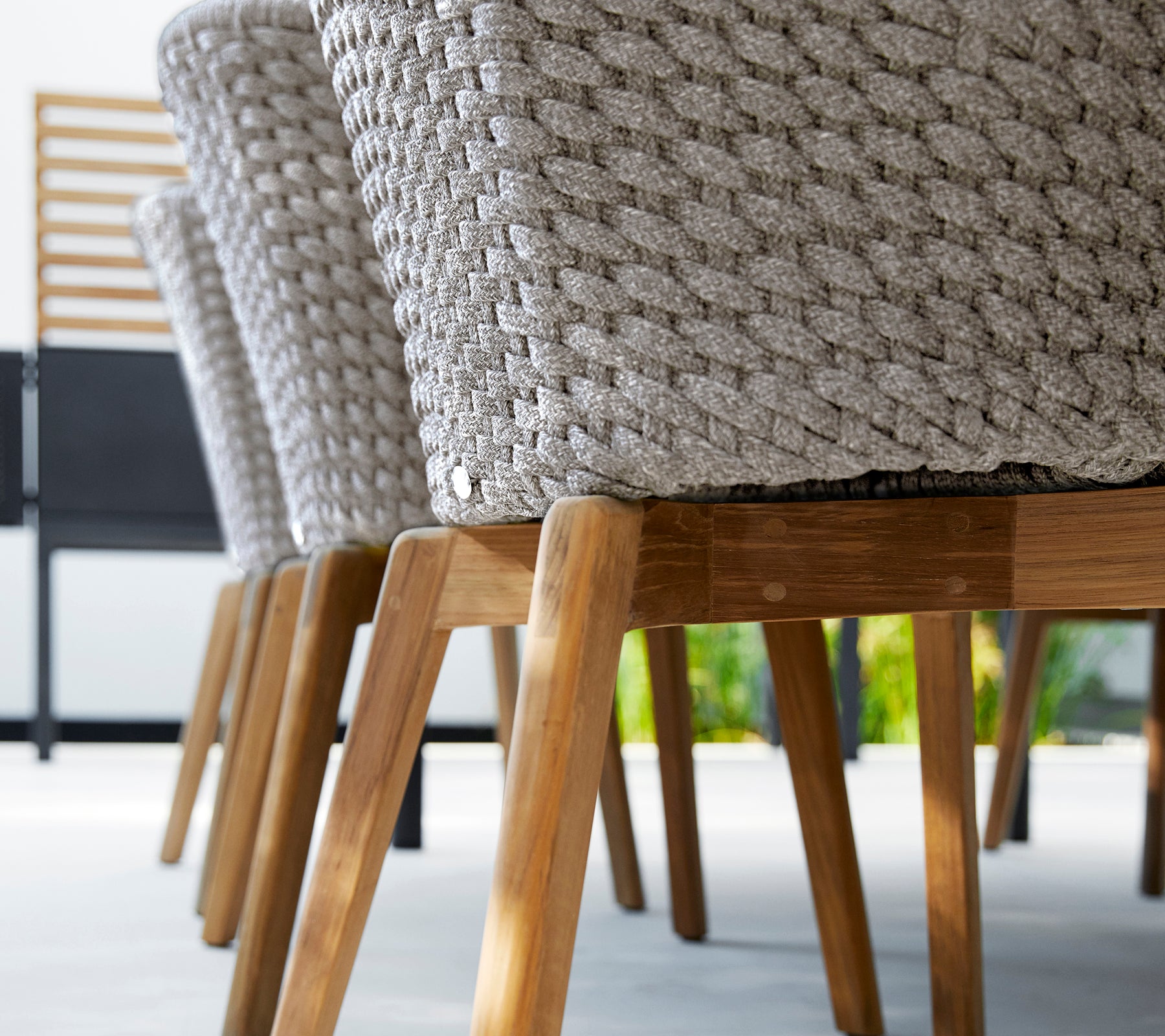 Moderne grauer Stuhl mit einem gewebten Design und Holzbeinen.