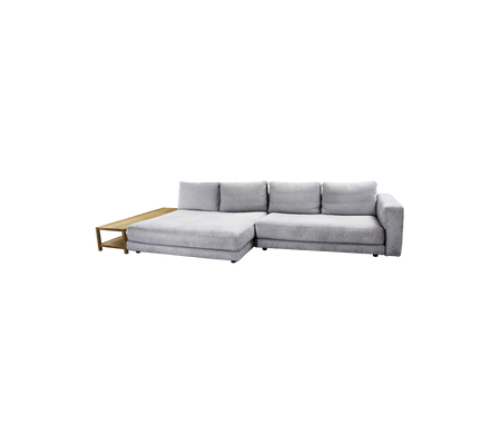 Ein modernes, graues Ecksofa mit plüschigen Kissen und einem schlanken Holztisch auf einer Seite.
