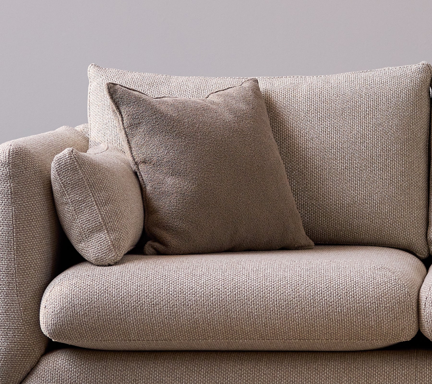Taupe Duft-Kissen auf einem weichen, strukturierten Sofa, das dem Sitzbereich eine gemütliche und stilvolle Note verleiht.