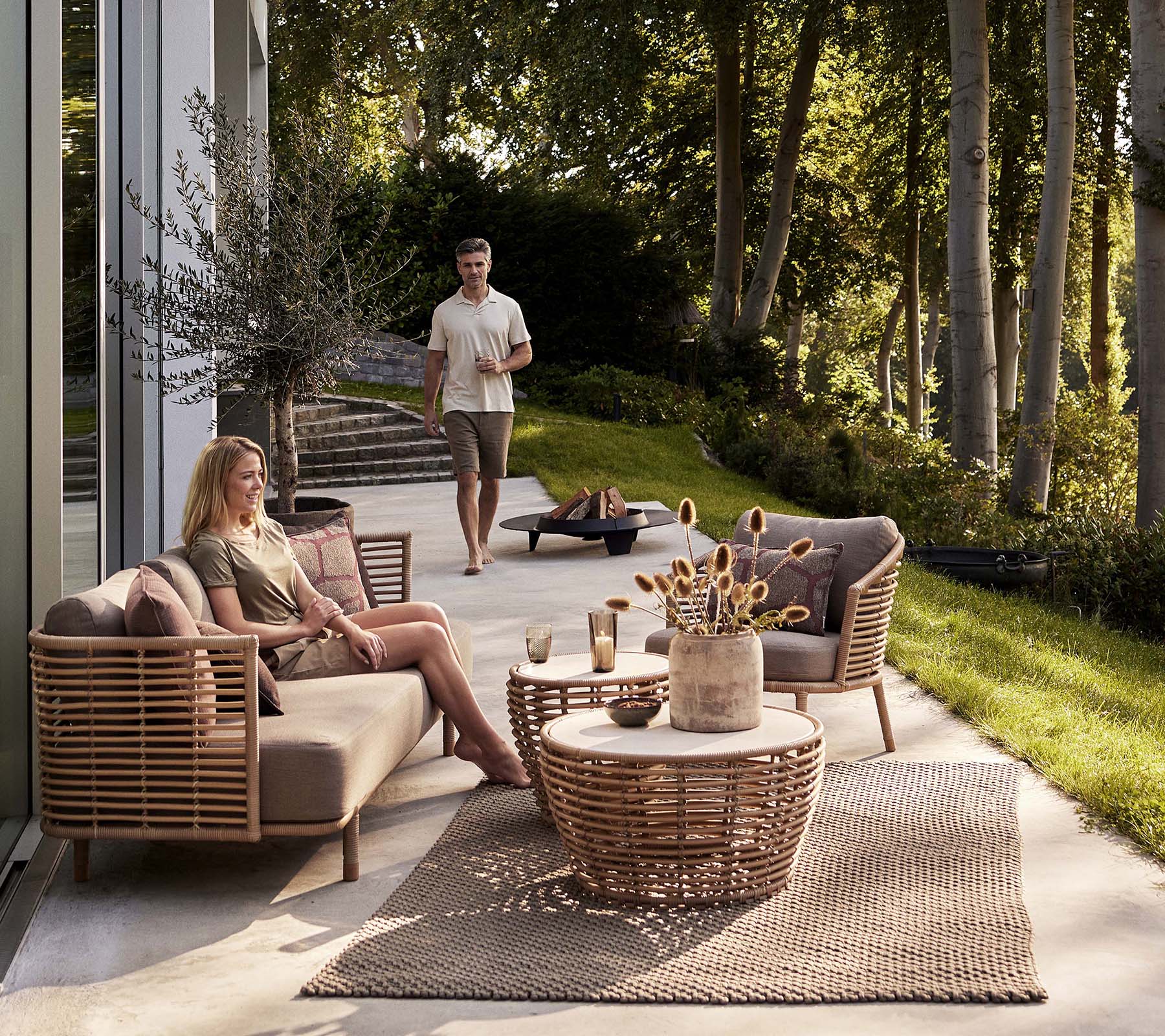Eine gemütliche Sitzecke mit einem Sense-Sofa und einem Lounge-Stuhl, begleitet von einem Korbkaffee-Tisch und dekorativen Elementen.