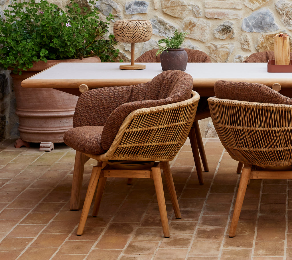 Elegante Essbereich mit Drehstühlen mit Teakbeinen um einen stilvollen Tisch, ergänzt durch dekorative Pflanzen und Accessoires.